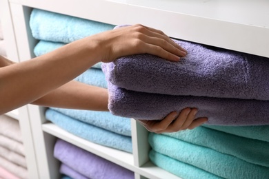 Photo of Woman putting towels on shelf, closeup view