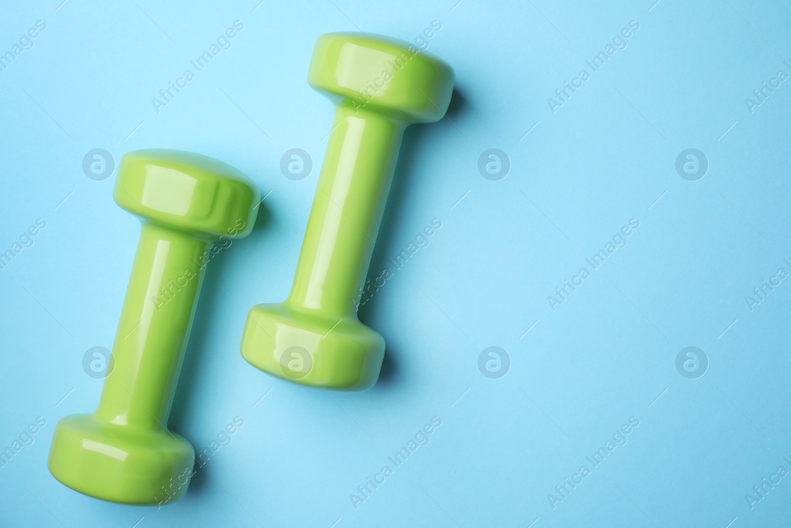 Photo of Bright dumbbells and space for text on color background, flat lay. Home fitness