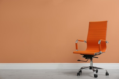 Modern office chair near orange coral wall indoors. Space for text