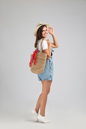 Photo of Young woman with stylish straw bag on light grey background