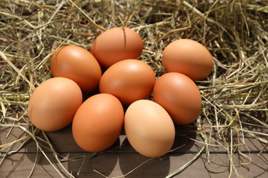Photo of Fresh chicken eggs and dried hay on wooden table