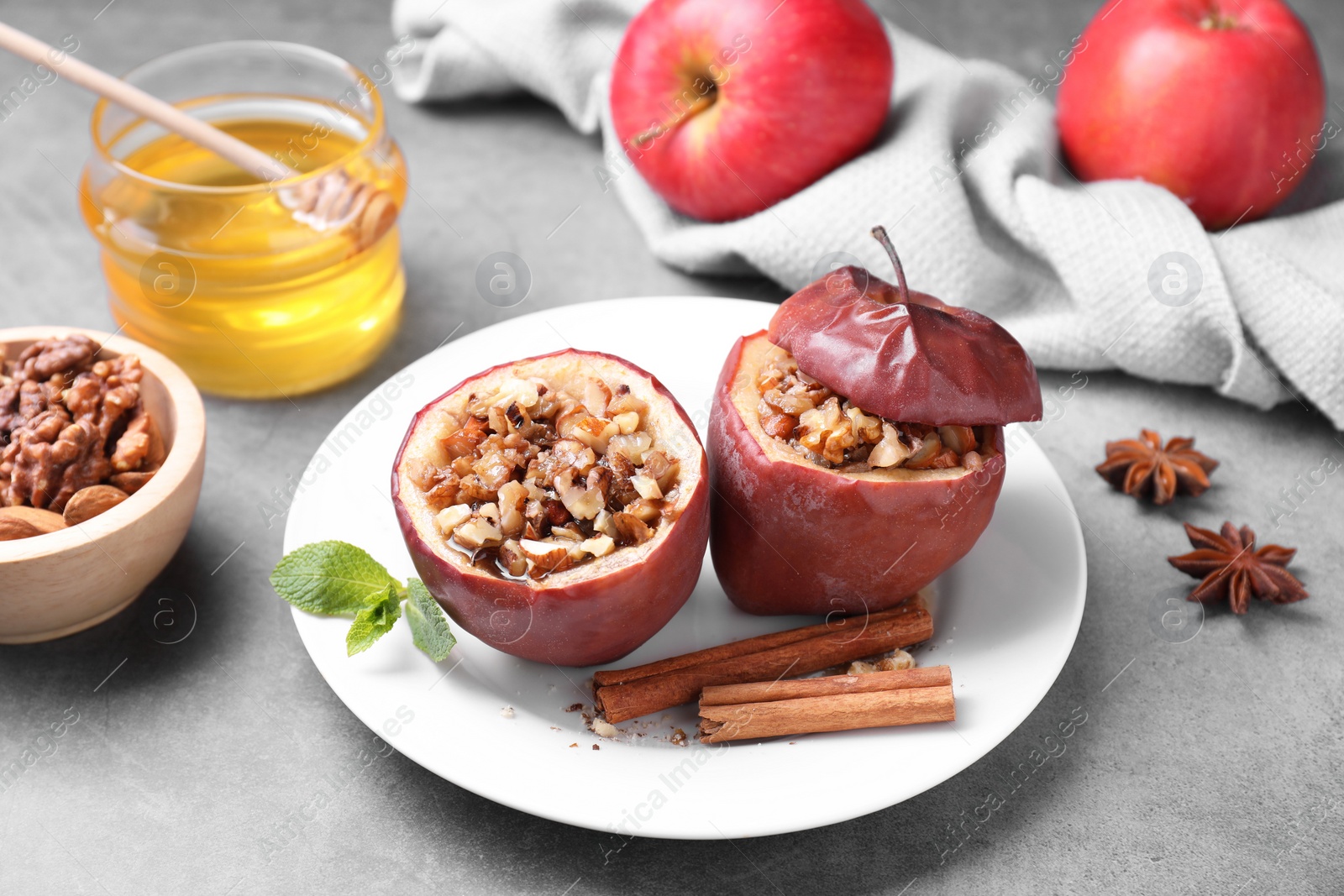 Photo of Tasty baked apples with nuts, honey and spices on gray table