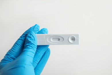 Photo of Doctor holding disposable express test for hepatitis on white background, closeup