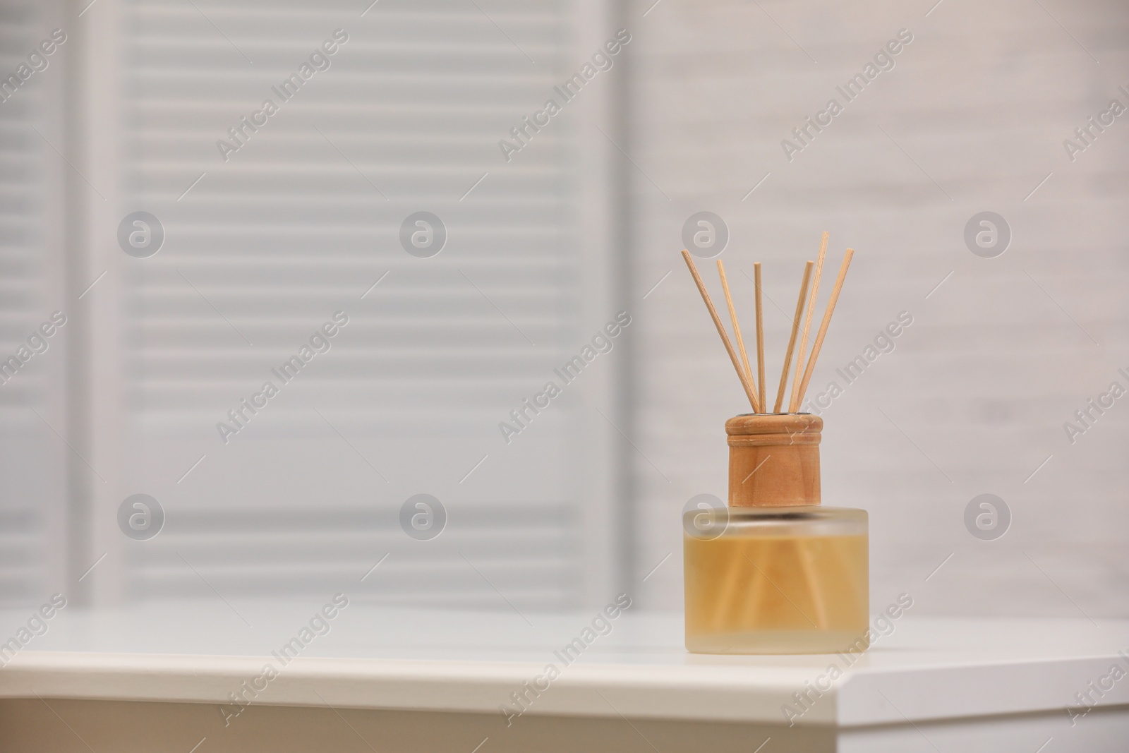 Photo of Reed air freshener with essential oil on table indoors. Space for text