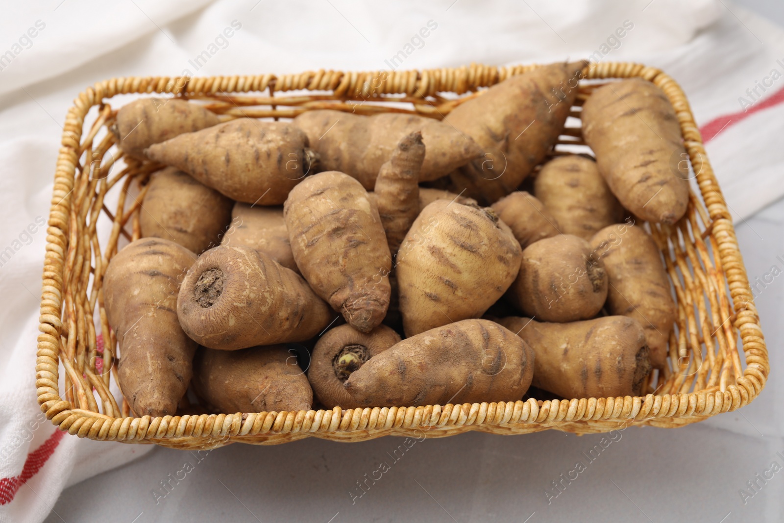 Photo of Tubers of turnip rooted chervil in wicker basket on table, closeup