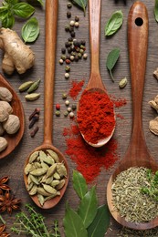 Photo of Different herbs and spices with spoons on wooden table, flat lay