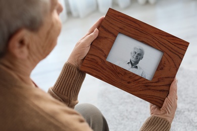 Photo of Elderly woman with framed photo of her son at home