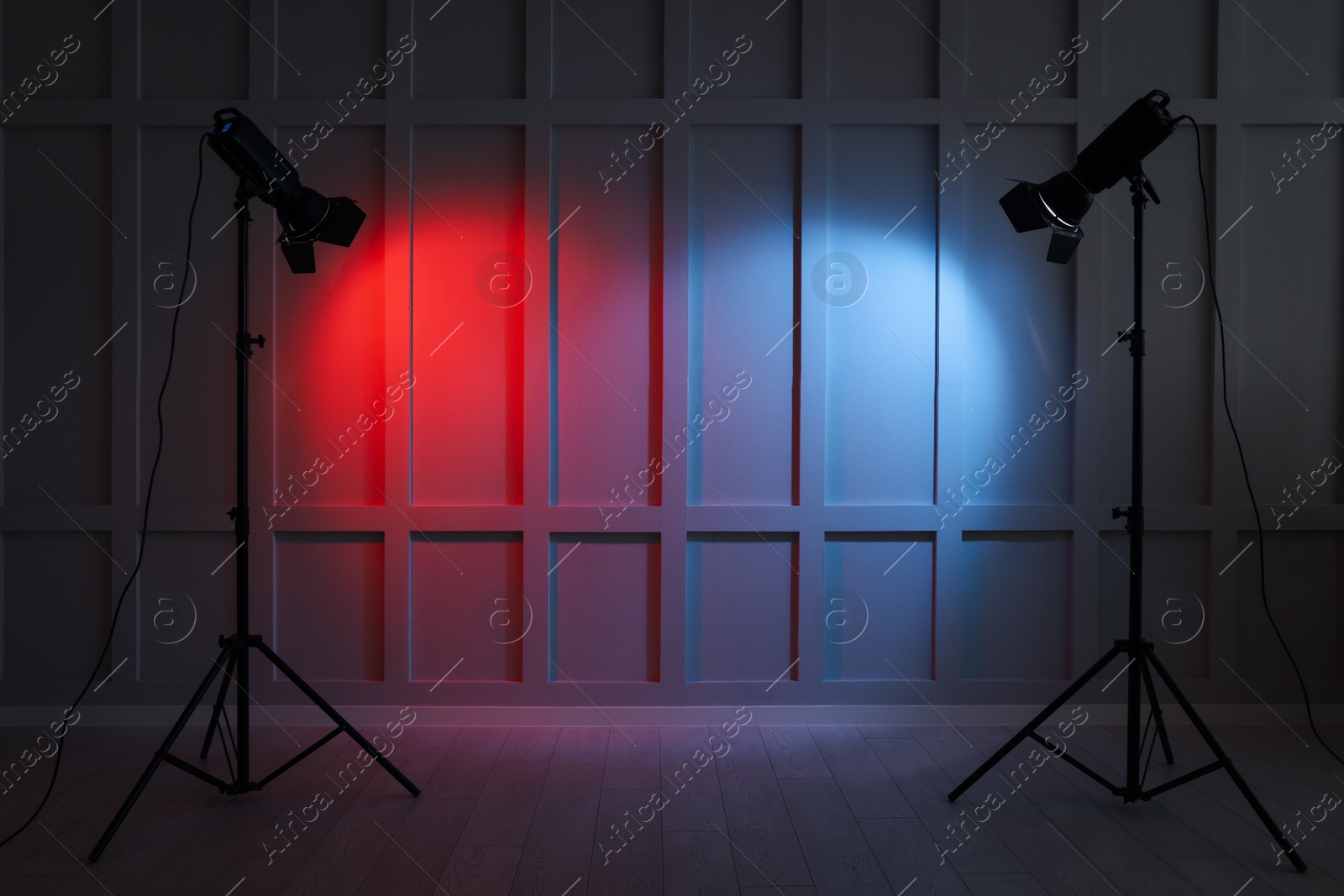 Photo of Bright red and blue spotlights near wall indoors, space for text