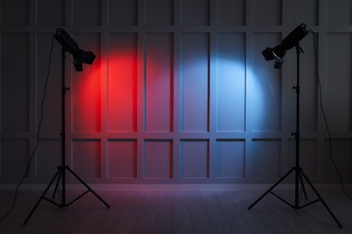 Photo of Bright red and blue spotlights near wall indoors, space for text