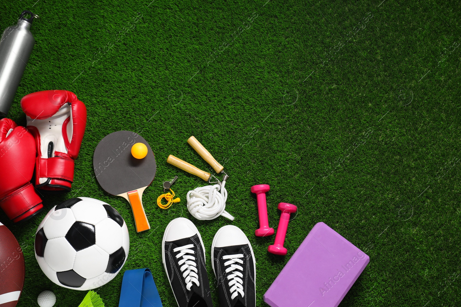 Photo of Different sports equipment on green grass, flat lay. Space for text