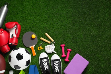 Photo of Different sports equipment on green grass, flat lay. Space for text