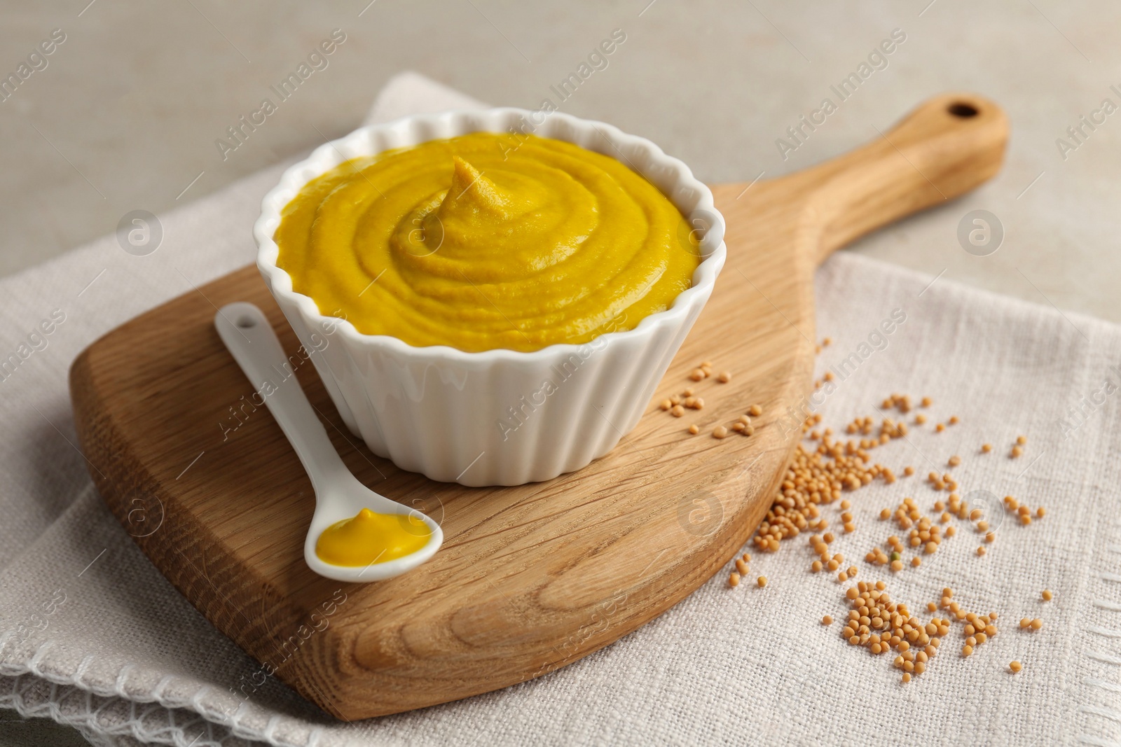 Photo of Tasty mustard sauce and dry seeds on light table