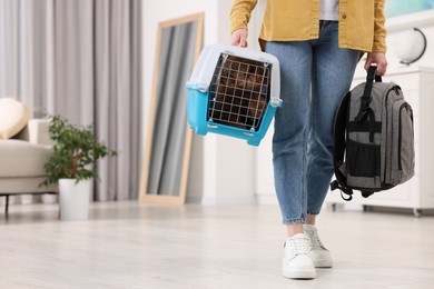 Photo of Travel with pet. Woman holding carrier with dog and backpack at home, closeup. Space for text