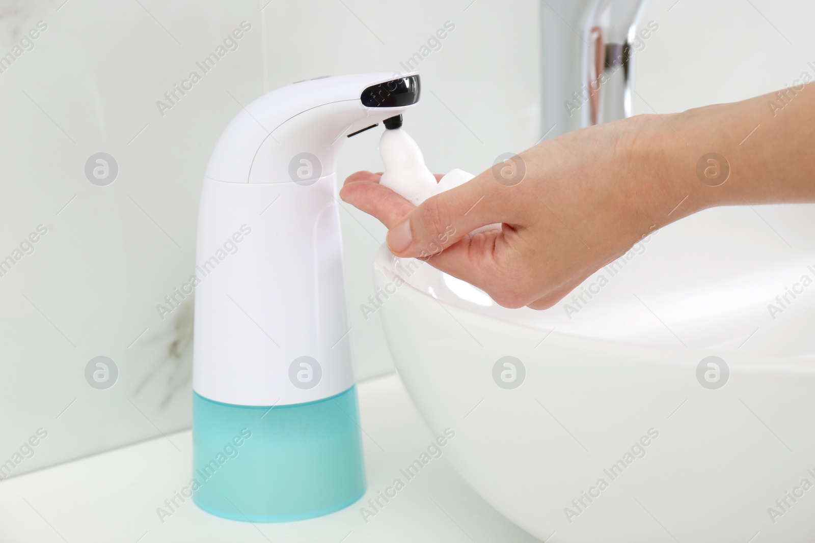 Photo of Woman using automatic soap dispenser in bathroom, closeup