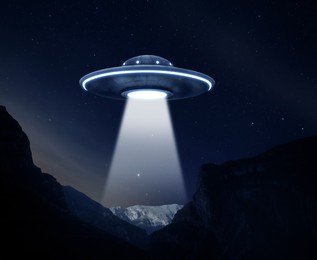 Image of UFO. Alien spaceship emitting light beam over mountains at night, illustration