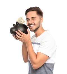 Photo of Portrait of young man holding piggy bank with money on white background