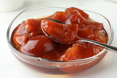 Photo of Quince jam in glass bowl on white table, closeup