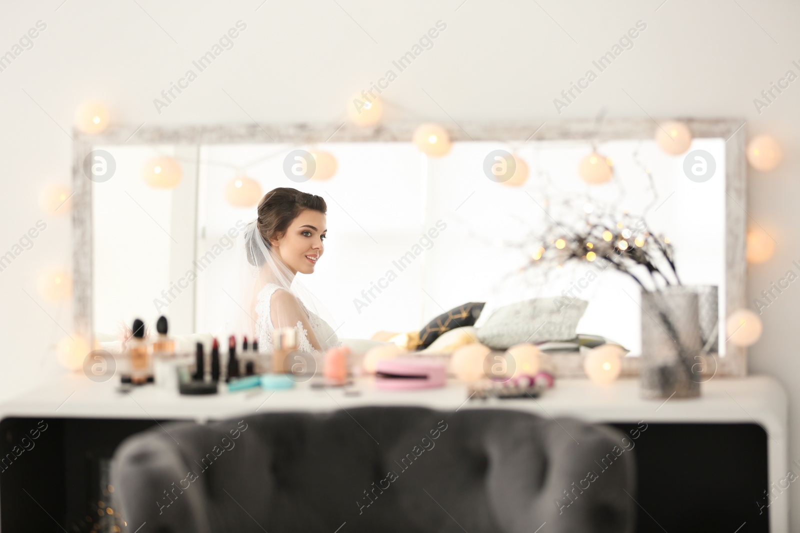 Photo of Reflection of beautiful young bride with makeup created by professional artist in mirror