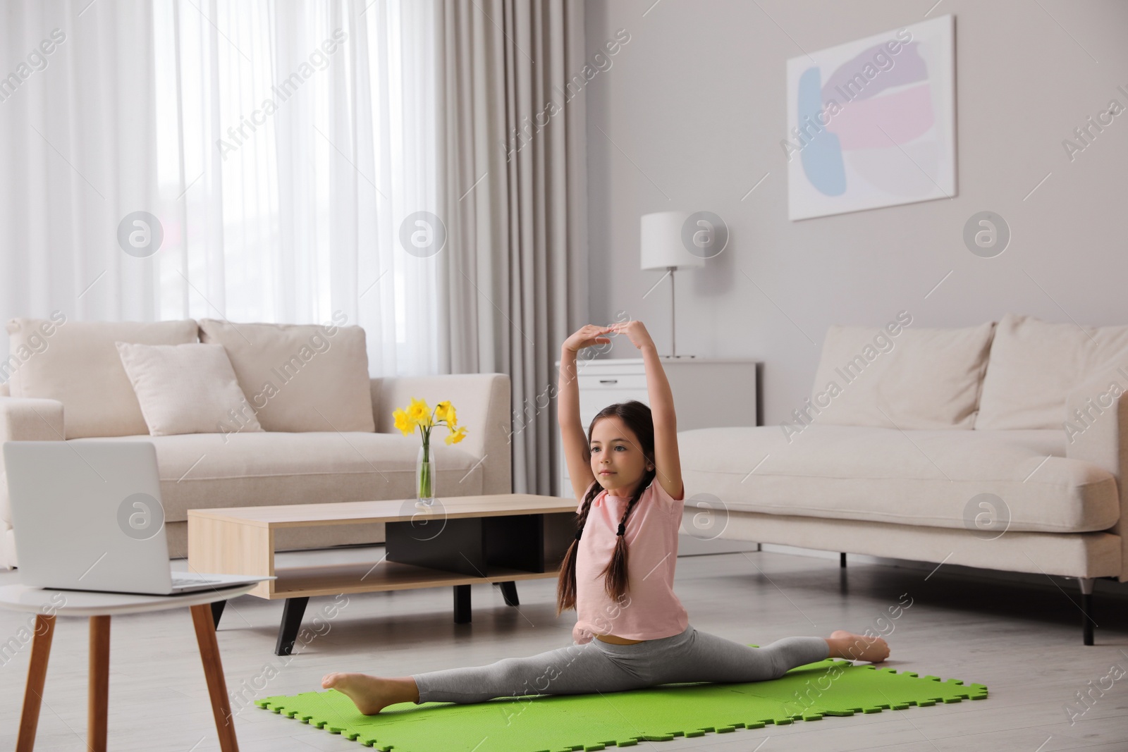 Photo of Cute little girl taking online dance class at home