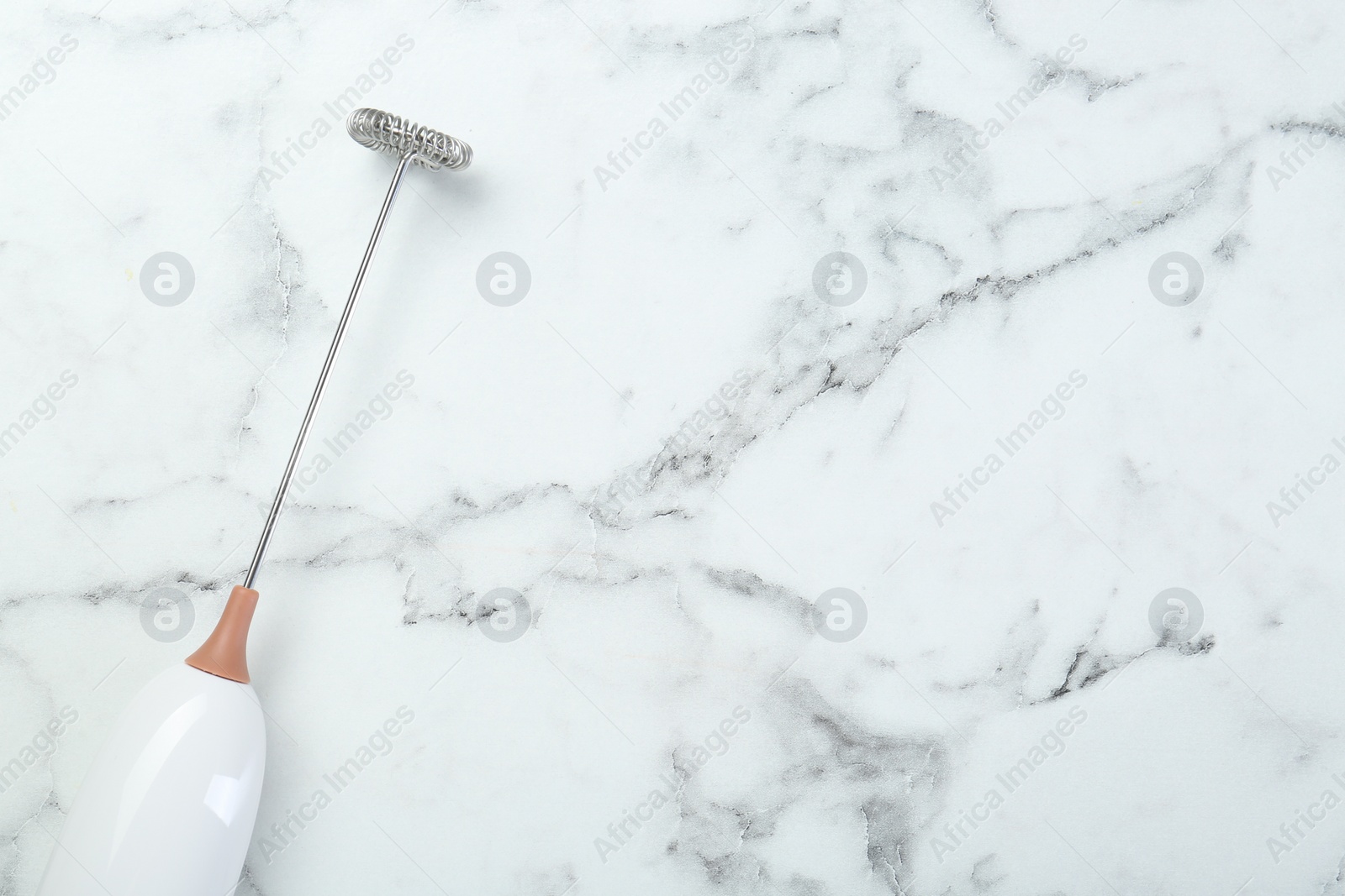 Photo of Milk frother wand on white marble table, top view. Space for text