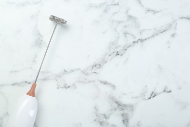 Photo of Milk frother wand on white marble table, top view. Space for text