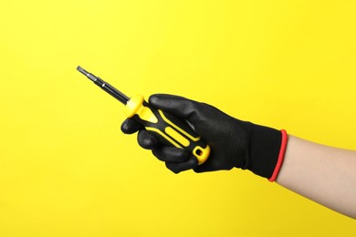 Photo of Woman holding screwdriver on yellow background, closeup