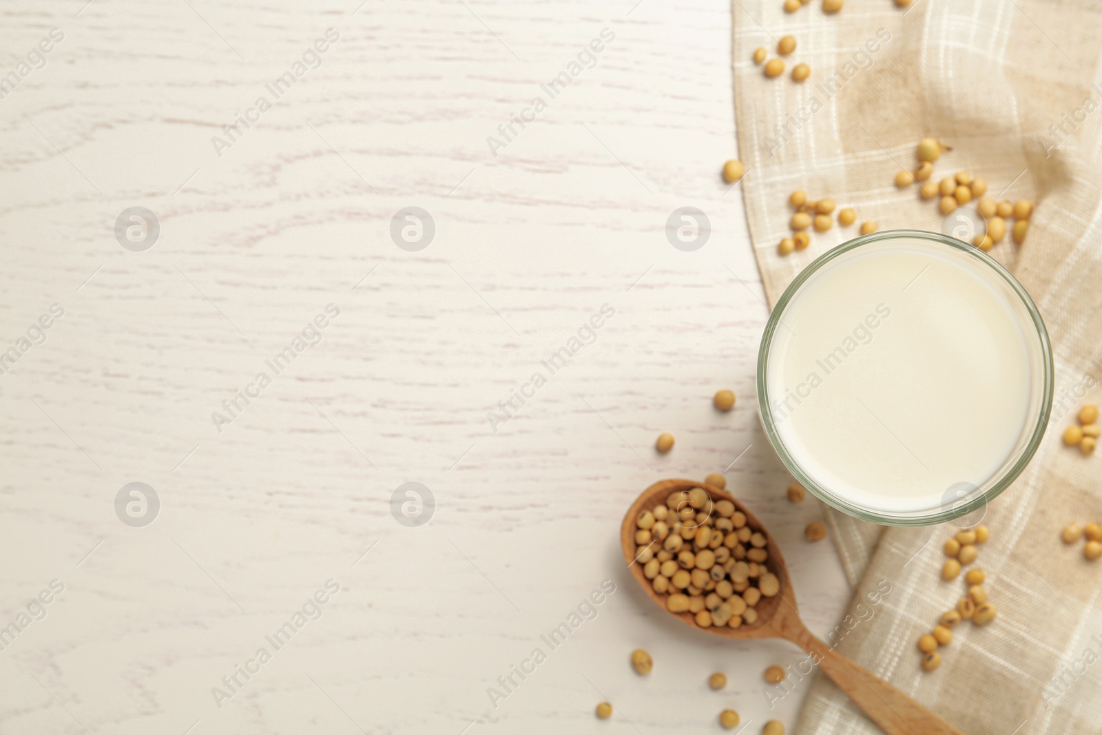 Photo of Glass with fresh soy milk and grains on white wooden table, flat lay. Space for text