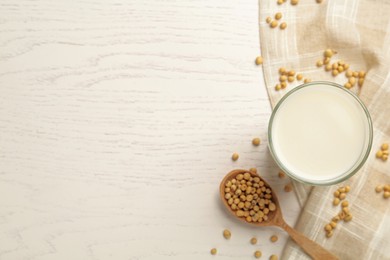 Glass with fresh soy milk and grains on white wooden table, flat lay. Space for text