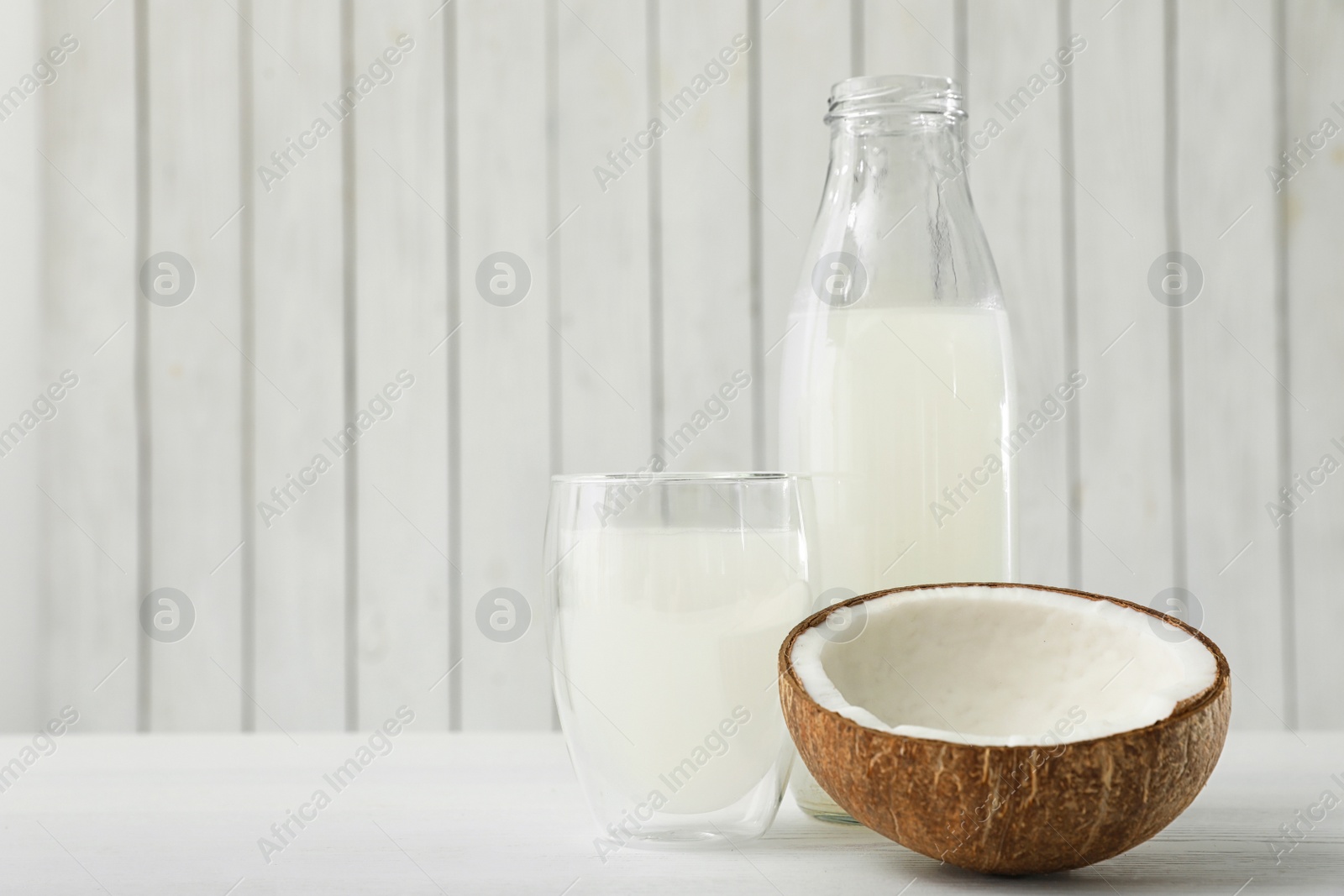 Photo of Composition with bottle and glass of coconut water on white wooden table. Space for text