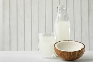 Composition with bottle and glass of coconut water on white wooden table. Space for text