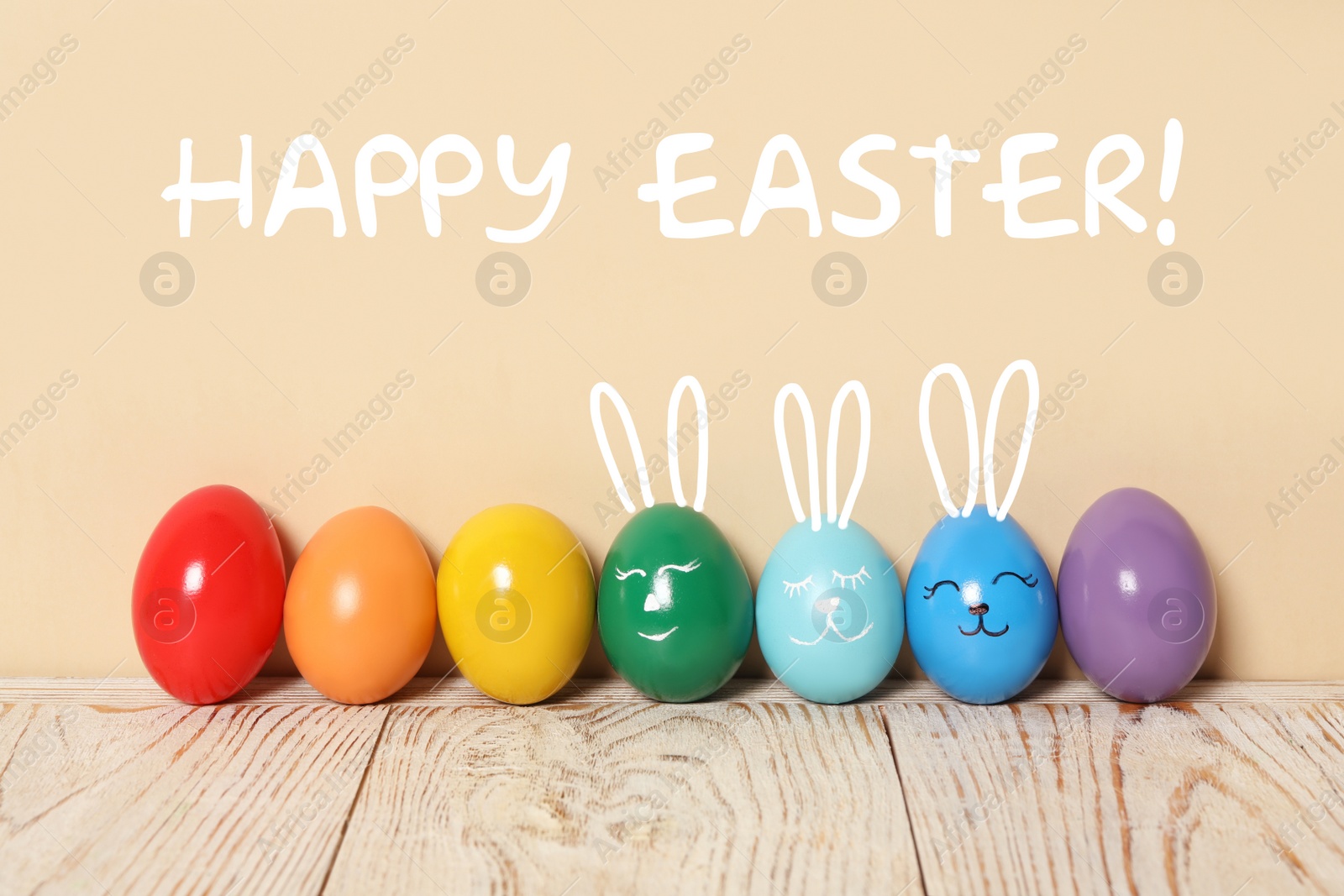 Image of Several eggs with drawn faces and ears as Easter bunnies among others on white wooden table against beige background