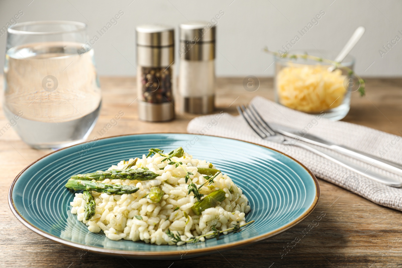 Photo of Delicious risotto with asparagus served on wooden table