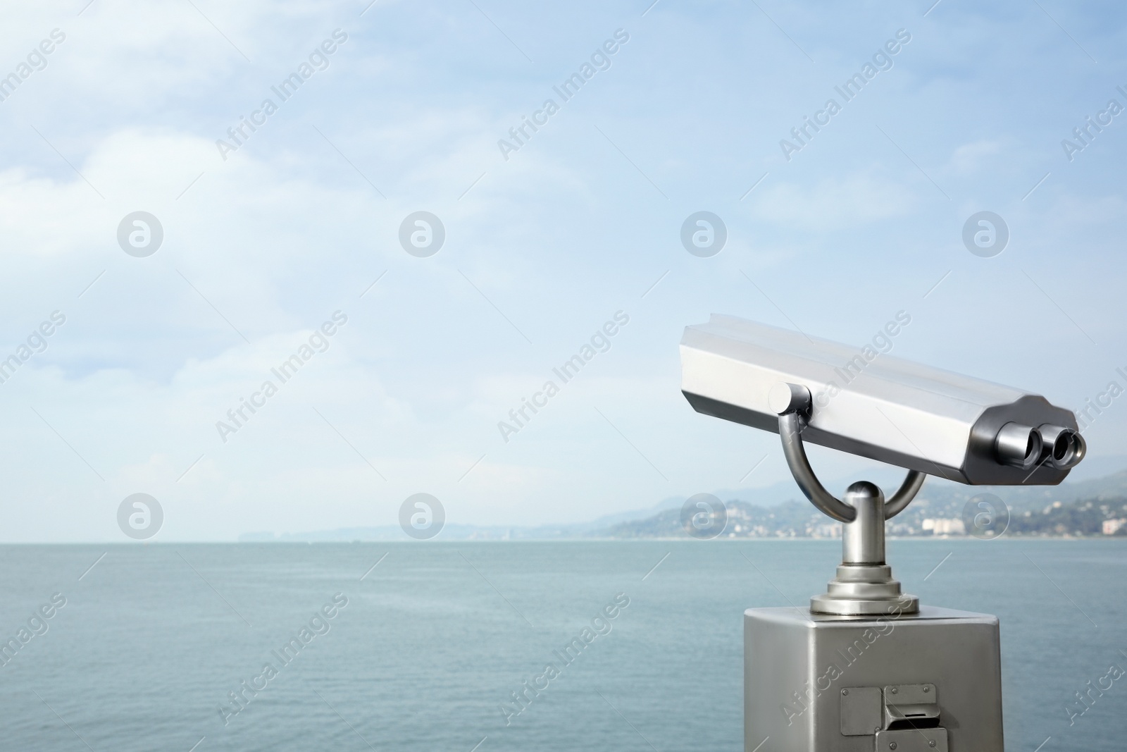 Photo of Metal tower viewer installed near sea, space for text. Mounted binoculars