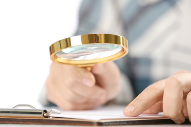 Woman using magnifying glass at table, closeup