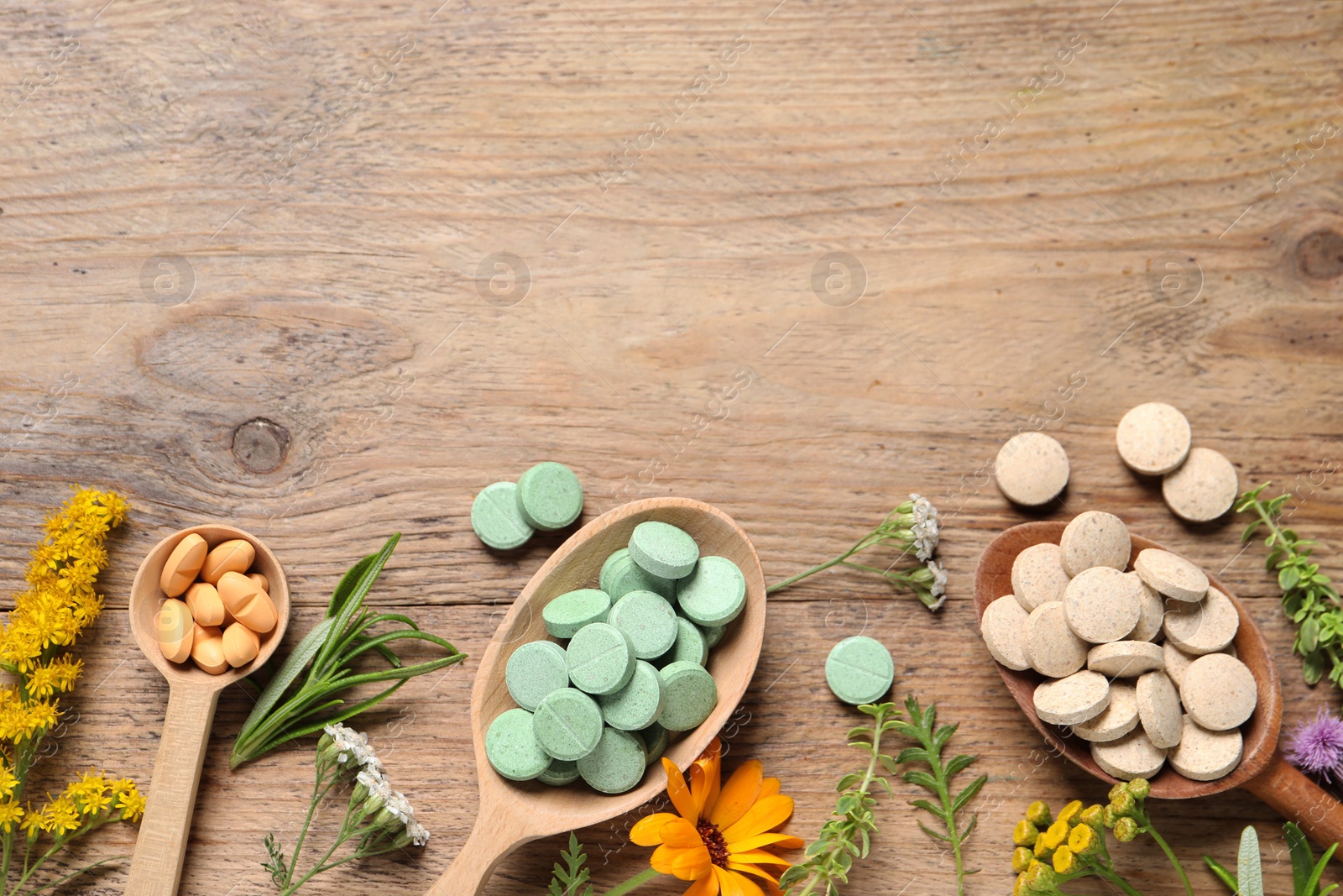 Photo of Different pills, herbs and flowers on wooden table, flat lay with space for text. Dietary supplements