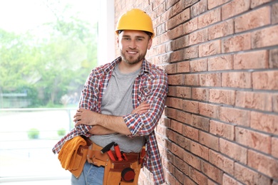 Photo of Young working man in hardhat near brick wall