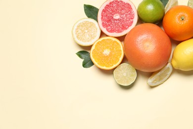 Photo of Different cut citrus fruits and leaves on beige table, flat lay. Space for text