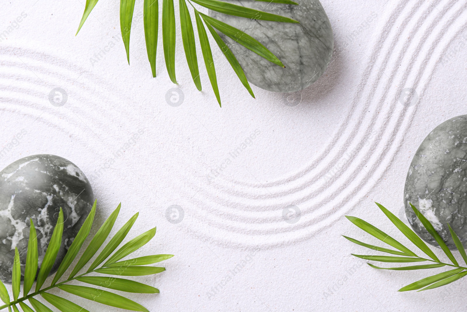 Photo of Zen concept. Stones, leaves and pattern on white sand, flat lay