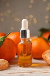 Bottle of tangerine essential oil and fresh fruits on white wooden table