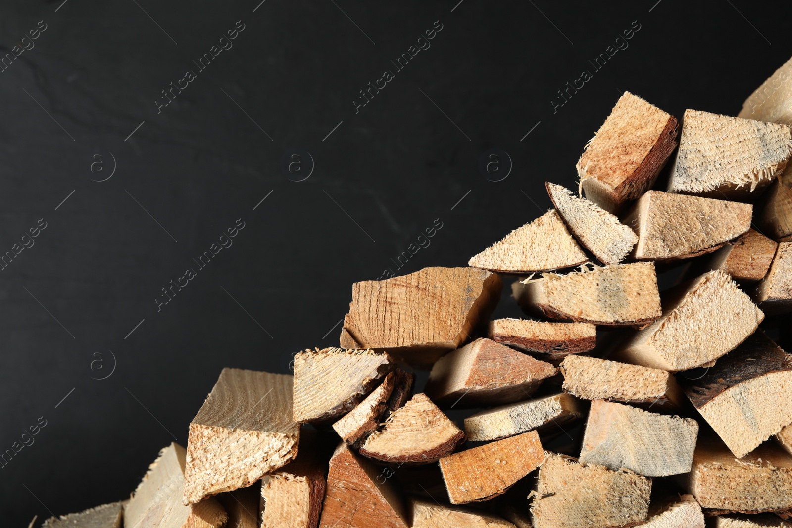 Photo of Cut firewood on black background. Space for text