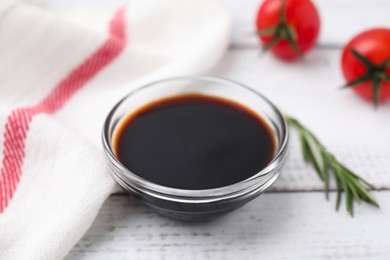 Bowl with balsamic vinegar, rosemary and tomatoes on white wooden table, closeup