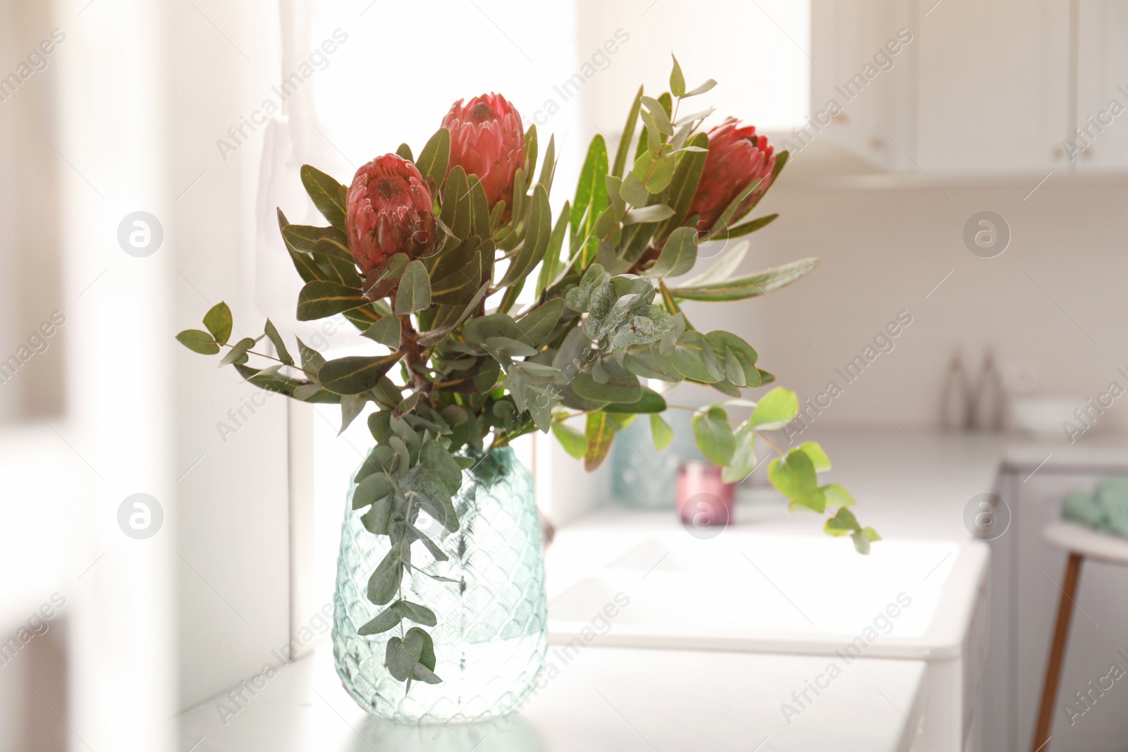 Photo of Bouquet with beautiful protea flowers on countertop in kitchen, space for text. Interior design