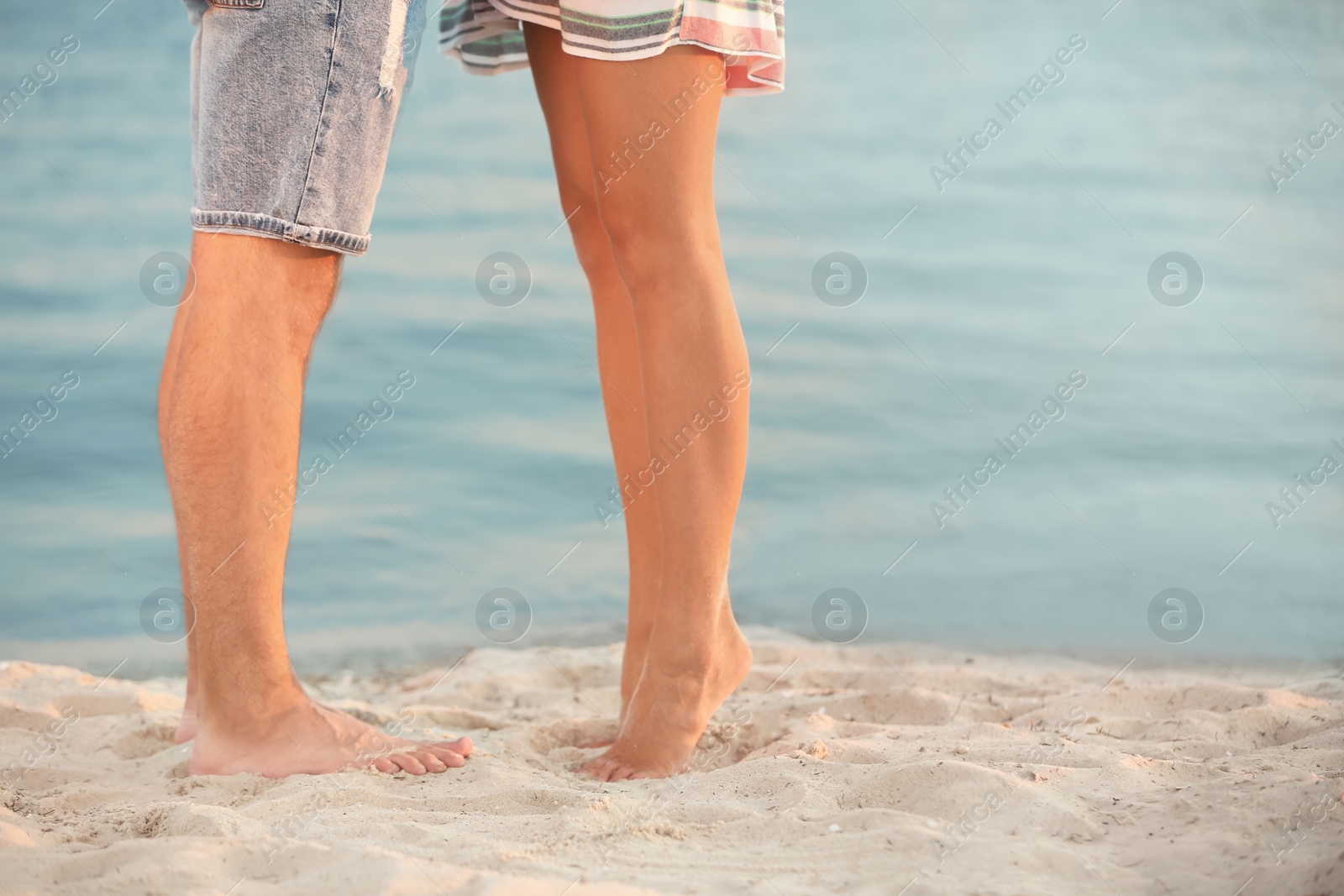 Photo of Happy young couple resting together on beach, closeup of legs