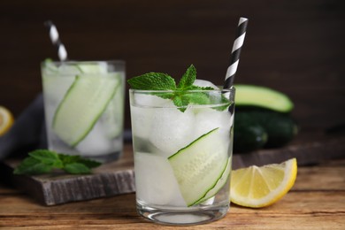 Photo of Glasses of refreshing cucumber water with mint on wooden table