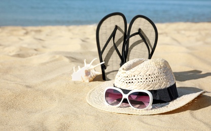 Photo of Stylish beach accessories on sand near sea