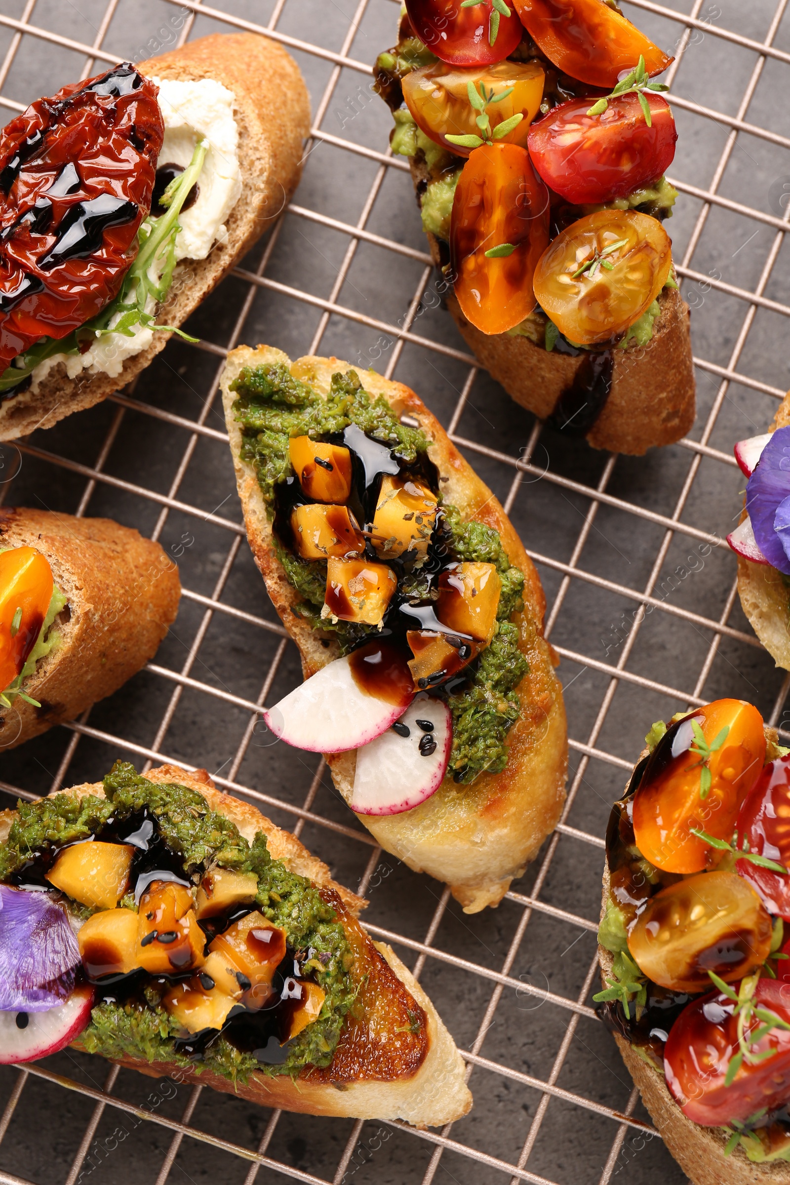 Photo of Delicious bruschettas with different toppings and balsamic vinegar on gray table, flat lay