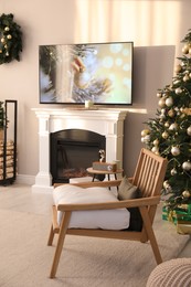 Modern TV set on light wall in room decorated for Christmas