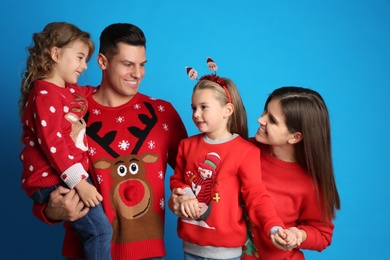 Family in Christmas sweaters on blue background
