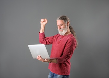 Photo of Portrait of handsome mature man with laptop on color background