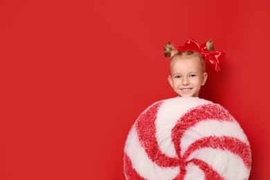 Image of Cute little girl dressed as candy on red background, space for text. Christmas suit